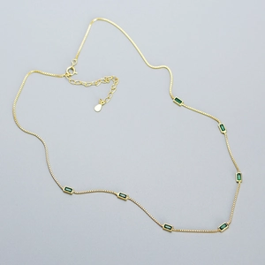 Detail of s925 silver gold chain necklace with seven rectangular emerald green zircons