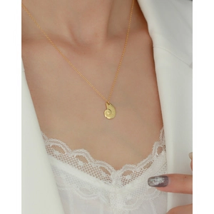 Detail of s925 silver golden conch necklace on model wearing white lace blazer