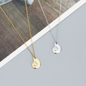 Macro shot of seashell pendant necklace with fine spiral textures in gold and silver finish