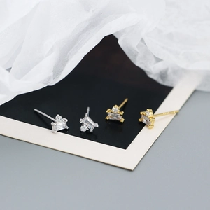 Macro shot of silver and gold geometric baguette zircon stud earrings on luxury paper