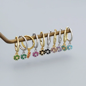 Detailed close-up of colorful daisy flower drop earrings on a vintage metal display stand