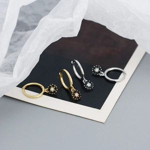 Close-up of gold and silver S925 earrings with zircon floral pendants and hoop design