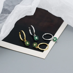 Detailed close-up of gold and silver S925 floral earrings with green zircon accents