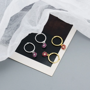 Macro detail of silver and gold floral hoop earrings with colorful zircon stone charms