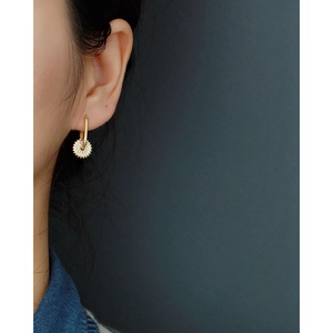 Gros plan d'un modèle portant une boucle d'oreille en U dorée avec un pendentif pavé