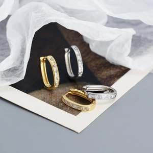 Macro shot of U-shaped hoop earrings with baguette cut clear cubic zirconia in gold and silver