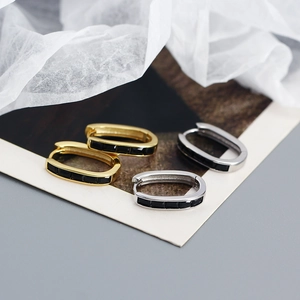 Macro detail of U-shaped earrings with black rectangular zircon in gold and silver finish