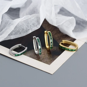 Detail of U-shape earrings with emerald green rectangular zircon in gold and silver