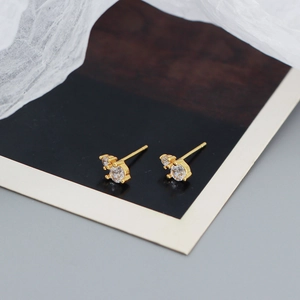 Macro shot of 925 silver stud earrings with three sparkling zircons in a gold finish