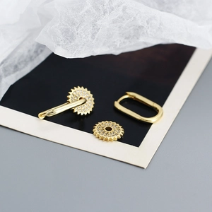 Détail de boucles d'oreilles dorées en U amovibles avec breloques engrenage en zircon