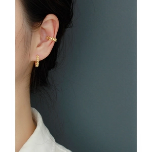 Close-up of gold chain link ear cuff and hoop earring set on a female model