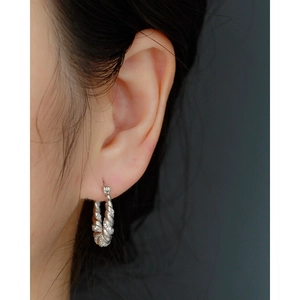 Close-up of S925 silver twisted U-shaped hoop earrings with micro-pave cubic zirconia