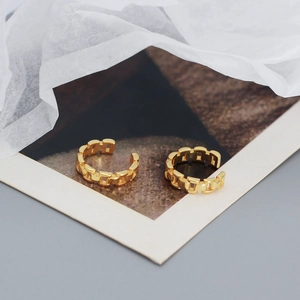 Detailed macro shot of the golden watch-chain style ear cuff with matte finish texture