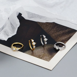 Nahaufnahme von S925 Huggie-Ohrringen in Gold und Silber mit Perlen und Zirkonia-Besatz