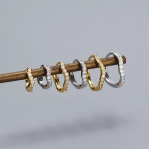 Close-up of S925 sterling silver stamp on wave-shaped hoop earrings with zircons