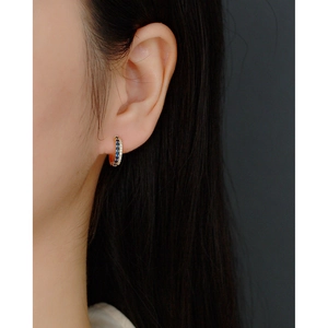 Detailed view of gold hoop earrings with double-row blue and white crystals on model