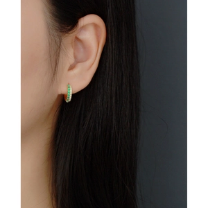 Detailed close-up of emerald and diamond double-row pave hoop earrings on model ear