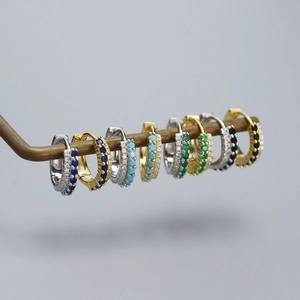 Close-up of multicolored gemstone huggie earrings in gold and silver plating