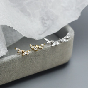 Dettaglio macro di orecchini a lobo a ramo d'ulivo con zirconi marquise in oro e argento