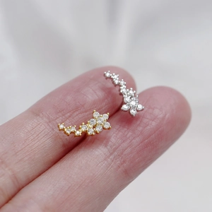 Macro shot showing small curved s925 silver stud earrings with pavé zircons on fingertips
