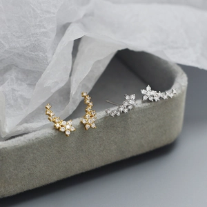 Macro view of gold and silver S925 floral star stud earrings with sparkling cubic zirconia