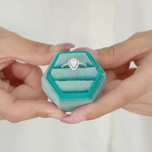 Detailed view of teardrop halo ring presented in a green velvet hexagonal gift box