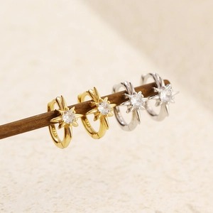 Detail view of gold and silver S925 sterling silver star hoop earrings with zircon