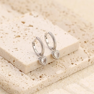 Macro detail of S925 silver hoop earrings featuring twisted texture and heart zircon charms
