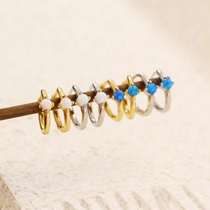 Close-up of gold and silver S925 earrings featuring white and blue opal stones