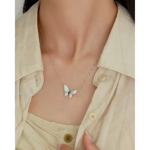 Détail d'un collier papillon en argent S925 avec nacre blanche et pierre verte sur un mannequin