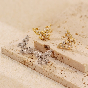Close-up of gold and silver butterfly stud earrings with sparkling cubic zirconia on stone