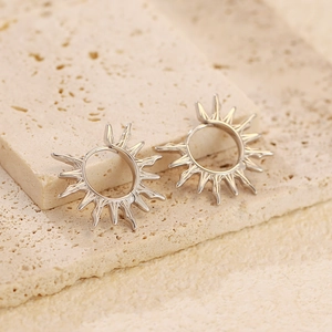 Vue macro de boucles d'oreilles soleil argentées sur socle en pierre au style bohème