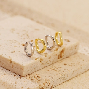 Macro shot of irregular wavy S925 sterling silver hoop earrings in gold and silver