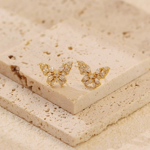 Macro view of butterfly earrings with marquise zircons on a textured stone stand