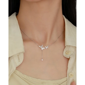 Close-up of s925 silver butterfly necklace with pearls and tassels on model neck