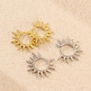 Boucles d'oreilles créoles soleil en argent S925 doré et argenté sur fond texturé