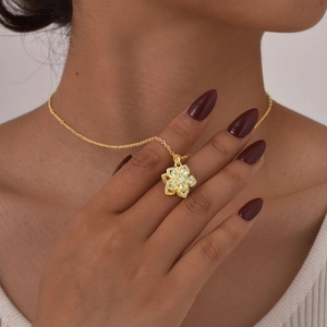 Detail showing a golden spinning flower necklace with pink zircons on a model