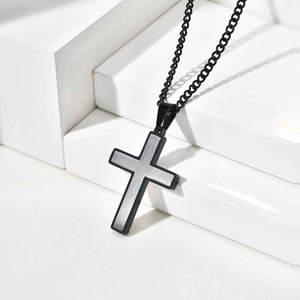 Detail of two-tone stainless steel cross pendant with black frame and brushed silver panel
