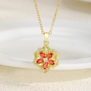 Macro shot of gold plated necklace with red zircon rotating flower pendant detail