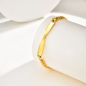 Detail view of gold stainless steel Mobius bracelet on a minimalist white display