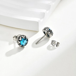 Détail d'une boucle d'oreille en acier titane avec zircon bleu et gravures vintage