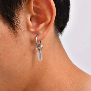 Gros plan détaillé d'une boucle d'oreille rasoir en acier inoxydable sur un mannequin homme