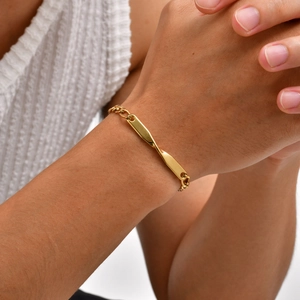 Detail of a golden Mobius bar bracelet with NK curb chain on a wrist with white knitwear