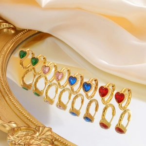 Detail van veelkleurige hart-zirkonia oorringen op een vintage gouden spiegel en zijde