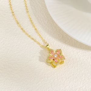 Detail of pink zircon flower pendant with gold plated chain on elegant white background