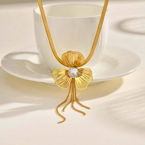 Macro detail of golden clover pendant with zircon center and fine fringe tassels on a chain