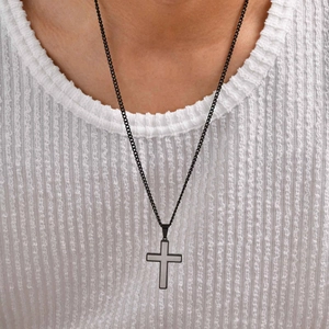 Detail of two-tone stainless steel cross pendant on black chain worn by a model
