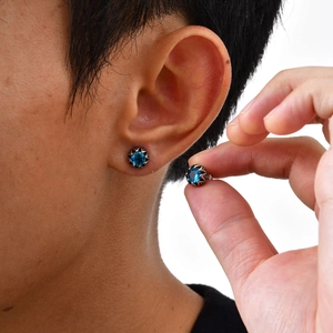 Gros plan de boucles d'oreilles en acier titane avec zircon bleu et monture étoile