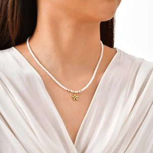 Gros plan d'un collier de perles blanches élégant avec pendentif fleur dorée sur un mannequin