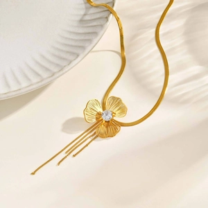 Detail of golden clover pendant with zircon center and cascading blade chain tassels